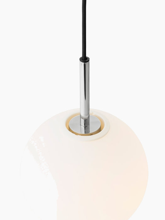 Detail shot of the illuminated TR Bulb Pendant, with a glowing opal glass bulb, polished steel fixture and black cord.