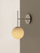 TR Bulb, Suspended Wall Lamp in polished steel, with a glowing opal glass bulb, on a two-toned white and taupe wall.