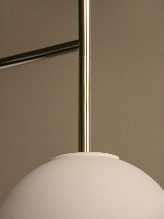 Close-up of the TR Bulb, Suspended Wall Lamp showing the polished steel fixture connected to the large round white opal bulb.