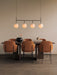 A TR Bulb Suspension Frame hangs over an Androgyne Dining Table with Penguin Dining Chairs. A black Surround Vase is on it.