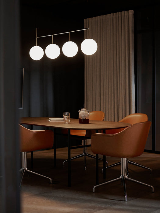 The TR Bulb Suspension Frame lights a Snaregade Oval Table and tan leather Harbour Swivel Chairs in a dimly lit, modern room.
