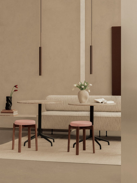 A serene dining space with two Tubulaire Pendant Lamps, a beige Eave Dining Sofa, and Passage Stools with pink upholstery.