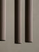 A close-up of three Tubulaire Pendant Lamps showing the reeded texture of the bronzed brass aluminium against a grey wall.