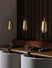 Three brass and walnut Umanoff Pendants hang over wooden tables in a sophisticated, dimly lit restaurant setting.