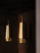 A close-up of two Umanoff Pendants hanging in a dark room, highlighting their warm glowing brass shades and walnut tops.