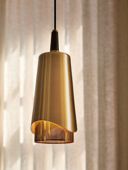 A close-up view of the Umanoff Pendant, featuring a brushed brass shade, a dark walnut top, and glowing perforated diffuser.