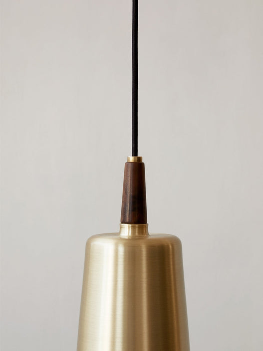 Close-up of the Umanoff Pendant, showing the brushed brass lampshade connected to a dark walnut wood piece and a black cord.