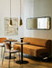 A modern dining area with two Umanoff Pendants, an Eave Dining Sofa, a Co Chair, a Column Table Lamp, and a Nimbus Mirror.