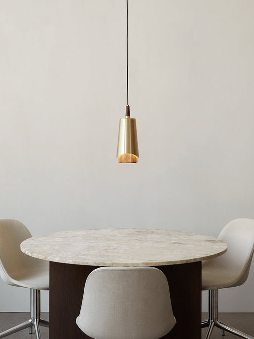 The Umanoff Pendant in brass and walnut hangs illuminated over a round marble dining table with three light-coloured chairs.