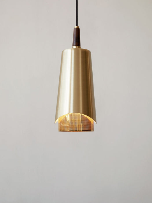 Close-up of the Umanoff Pendant light. The lamp has a brushed brass shade, walnut top, and a glowing perforated diffuser.