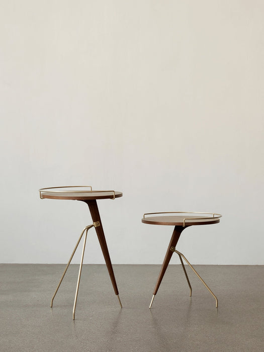 Two Umanoff Side Tables, in different heights, with dark walnut tops and brass tripod legs, against an off-white wall.