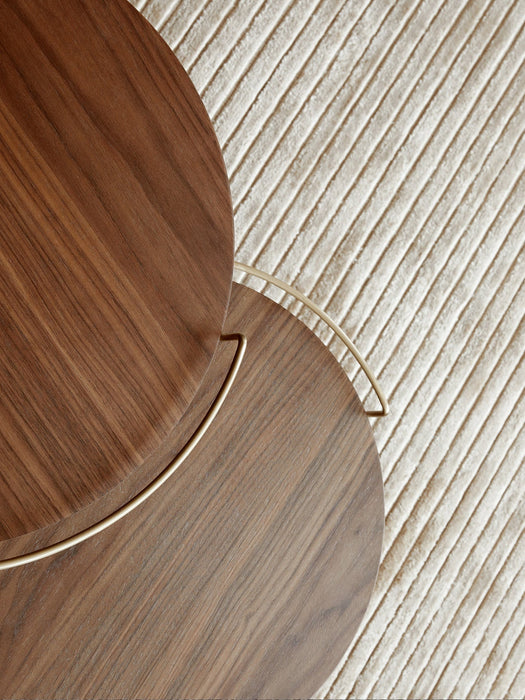 Overhead detail of two Umanoff Side Tables in walnut with brass accents, showing the wood grain on a textured cream rug.