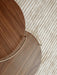 Overhead detail of two Umanoff Side Tables in walnut with brass accents, showing the wood grain on a textured cream rug.