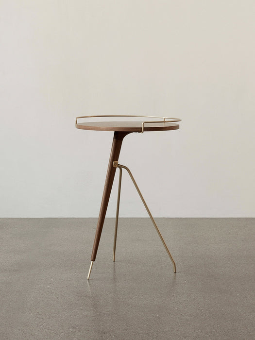 The Umanoff Side Table with a tripod base of brass and walnut, supporting a round walnut top with a brass rail.