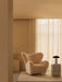 A tranquil, beige-toned room with The Tired Man armchair next to the Volume Side Table holding a Reverse Table Lamp.