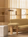 Angled view of the silver Volume Side Table next to the light green Brasilia Sofa, with a Wing Floor Lamp in a warm setting.