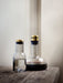 A large glass Menu Wine Breather Carafe filled with red wine sits next to a smaller matching water carafe on a wood surface.