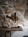 The Wine Breather Carafe on a rustic wooden table against a stone wall, beside a lit candle, lamp, and glass of red wine.
