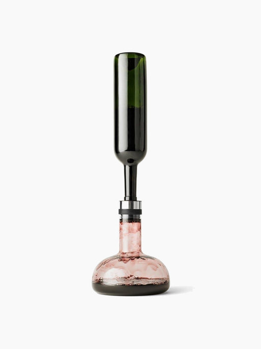Front view of the Wine Breather Carafe by Norm Architects, with an inverted wine bottle aerating rosé wine into the decanter.