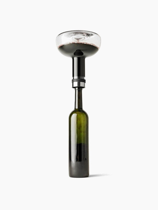A studio shot of the glass Wine Breather Carafe by Norm Architects aerating red wine from a bottle against a white background