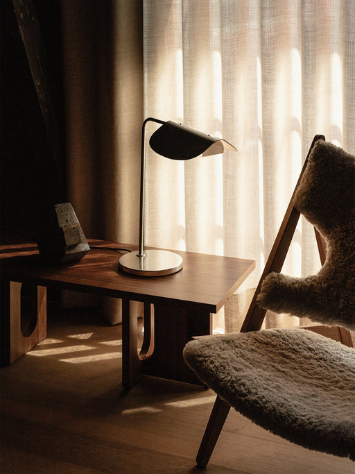 A living room scene featuring the Wing Table Lamp on an Androgyne Lounge Table beside a sheepskin Knitting Lounge Chair.