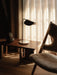 A living room scene featuring the Wing Table Lamp on an Androgyne Lounge Table beside a sheepskin Knitting Lounge Chair.