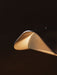 Close-up of the Wing Table Lamp's polished aluminium shade, showing its perforated pattern and warm glow from within.