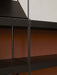 Close-up of a modern black shelving unit, highlighting the connection between the thin black metal frame and the shelves.