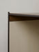 A detailed close-up of a furniture corner, showing the dark metal frame, dark wood surface, and beige textured fabric panel.