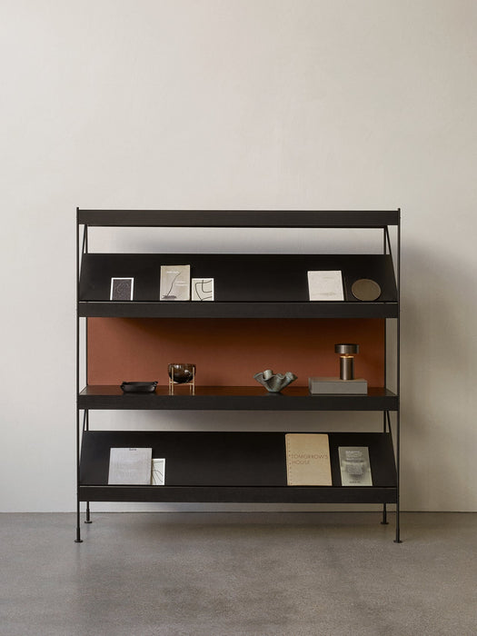 Front view of the black Zet Storage System with three shelves, styled with books, a small portable lamp, and ornaments.