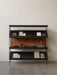 Front view of the black Zet Storage System with three shelves, styled with books, a small portable lamp, and ornaments.