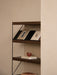 A close-up of the dark oak Zet Storage System with a black frame, styled with books and a small bowl against a neutral wall.