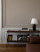 A Zet Storage System in dark oak wood, styled with books and a black lamp, sits against a taupe wall with white panelling.
