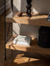 Sunlit close-up of the Zet Storage System's oak shelves and black frame, styled with books, a vase, and decorative objects.