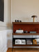 A detailed view of the dark wood Zet Storage System, styled with art books, ceramics, and a table lamp in a classic interior.