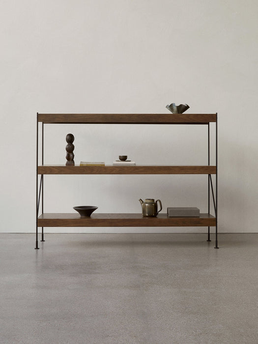 A three-shelf Zet Storage System in dark wood with a black metal frame, decorated with bowls, a teapot, and a sculpture.