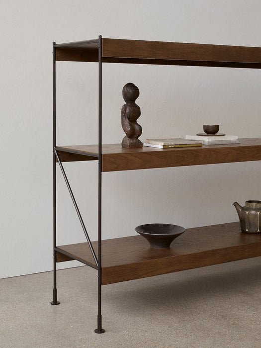 A side view of the Zet Storage System in dark oak with a black metal frame, styled with a sculpture, books and ceramics.