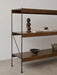A side view of the Zet Storage System in dark oak with a black metal frame, styled with a sculpture, books and ceramics.