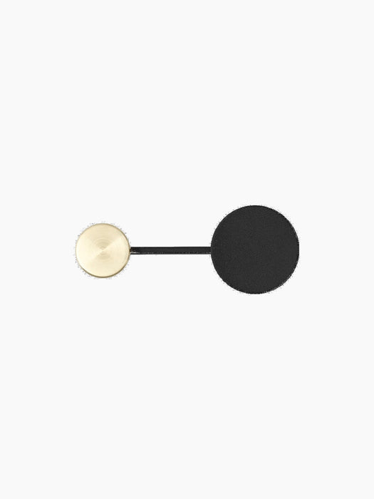 Top-down view of the small Afteroom Coat Hanger in black, with its large matte black disc and smaller brushed brass hook.