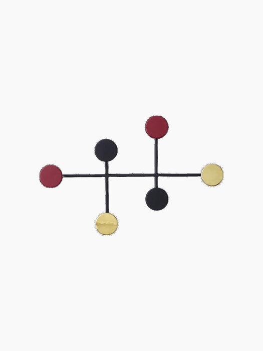 The Afteroom Coat Hanger, a black metal frame with six circular hooks in red, black, and brass against a black backdrop.