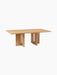 The Androgyne Rectangular Dining Table in natural oak. It has a long tabletop and two wide legs with sculptural cut-outs.