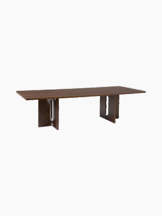 Angled view of the rectangular Androgyne Dining Table in dark stained oak, showing sculptural legs with large oval cut-outs.