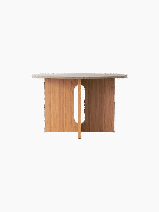 A front-on view of the round Androgyne Dining Table, featuring a Kunis Brescia stone top and a natural oak base with cutout.