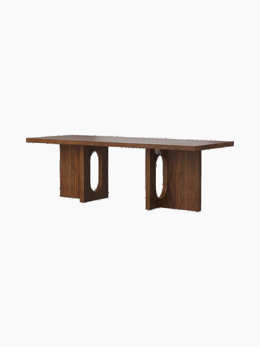 Angled view of the Androgyne Lounge Table in dark walnut, featuring a rectangular top and two block legs with oval cutouts.
