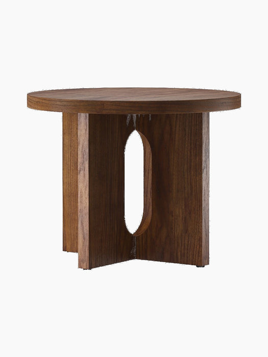 An angled shot of the round Androgyne Side Table, Ø50 in dark walnut. The base features wide legs and an oval cut-out.