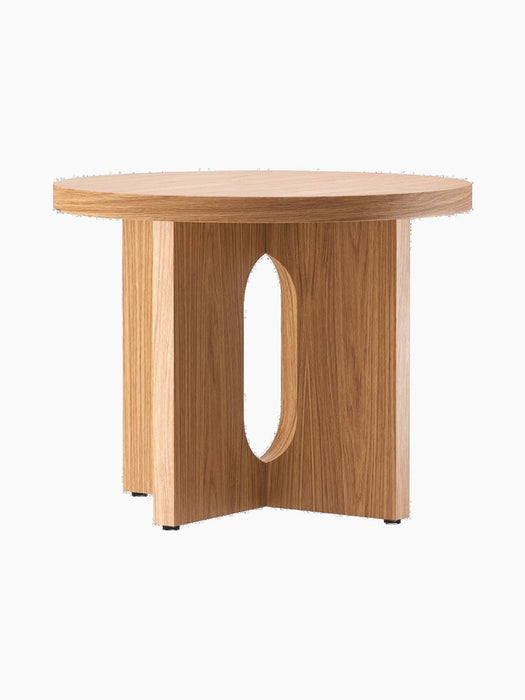 The Androgyne Side Table, Ø50, in natural oak, shown from an angle. It has a round top and a base with an oval cutout.