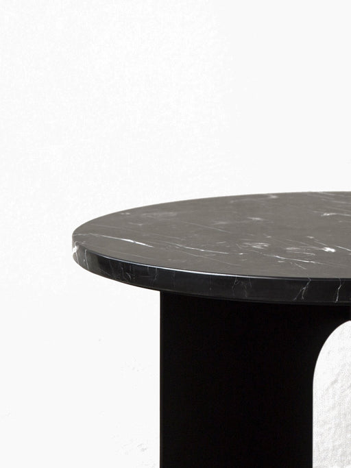 A close-up of the Androgyne Side Table, showing its round black marble top with white veining against a neutral background.