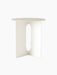 A front-facing image of the Androgyne Side Table. The piece is ivory-coloured with a round top and a base with oval cutouts.