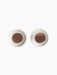 A top-down view of two Audo Bottle Grinders in sand-coloured ceramic, each featuring a dark wood top, on a black background.