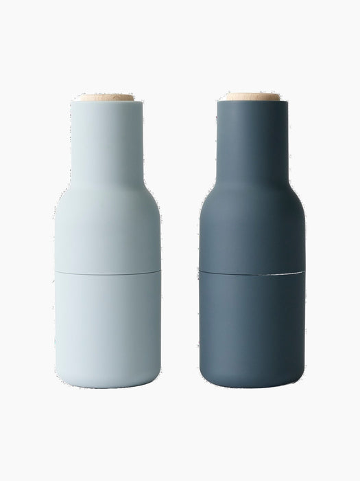 The Bottle Grinder set in light and dark blue. The minimalist, bottle-shaped grinders have matte finishes and wood tops.